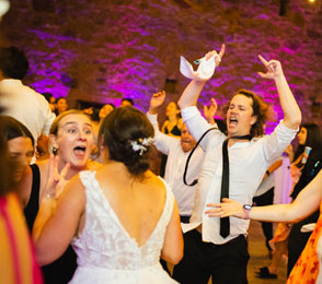 Candid wedding guests celebrating on the dance floor, showcasing joyful expressions and lively energy in a vibrant setting.