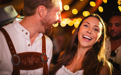 Smiling couple enjoying a lively event, surrounded by warm bokeh lights, capturing the authentic energy and joy of candid moments in lifestyle photography.