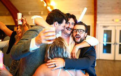 Candid moment of friends celebrating at a wedding reception in Westport, CT, showcasing joyful expressions and relaxed interactions, reflecting authentic event photography.