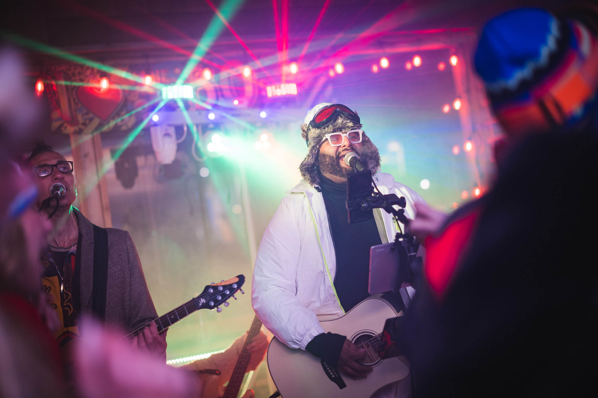 Live band performing at Après Ski event at The Bridge At Saugatuck, featuring colorful laser lights and a festive atmosphere, with musicians in winter attire engaging the audience.